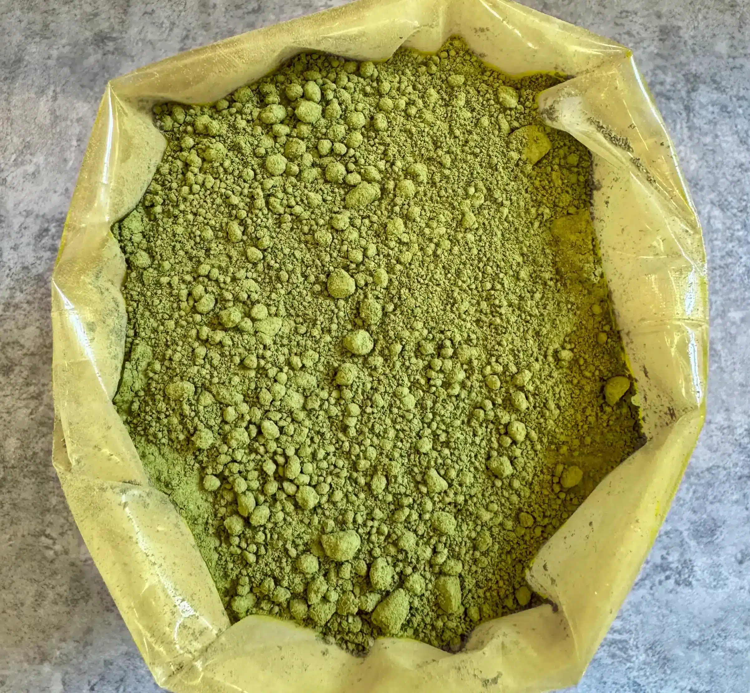 Poudre de kratom verte dans un sachet en plastique, vue du dessus