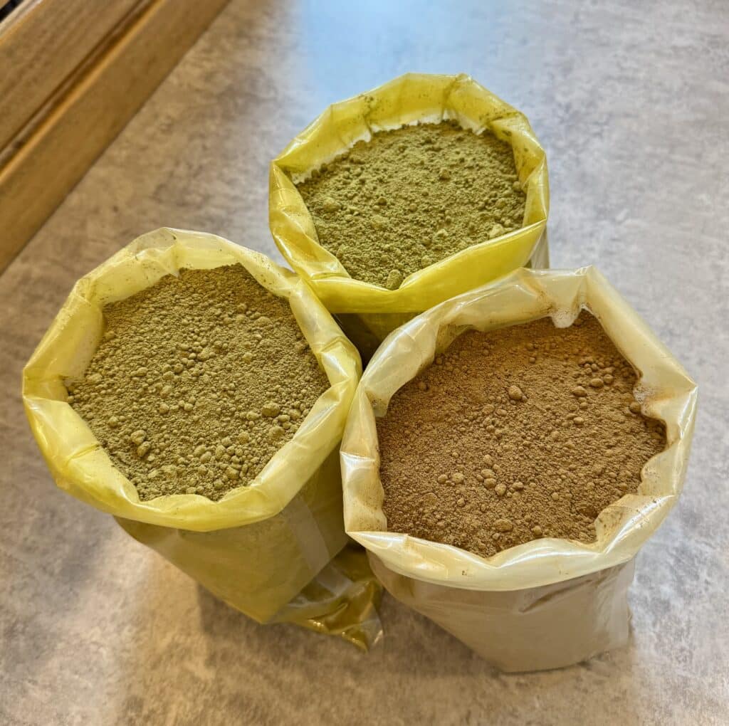 Lot de sachets de poudre de kratom verte, dorée et rouge, vue de profil