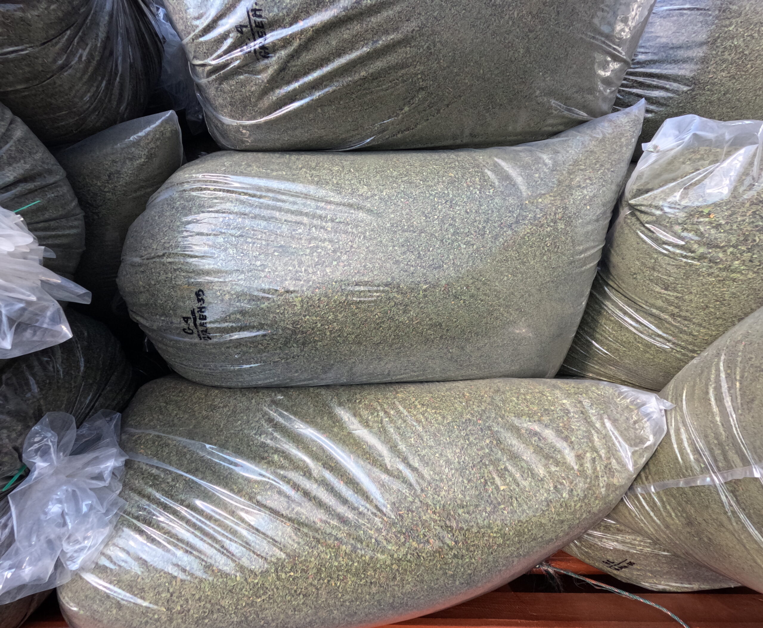 Gros plan sur une pile de sacs remplis de feuilles de kratom broyées, prêtes à être exportées